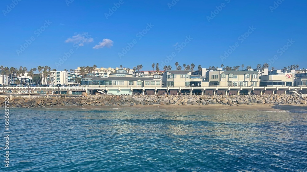 Obraz premium Coastal buildings and palm trees along the beachfront under clear blue sky