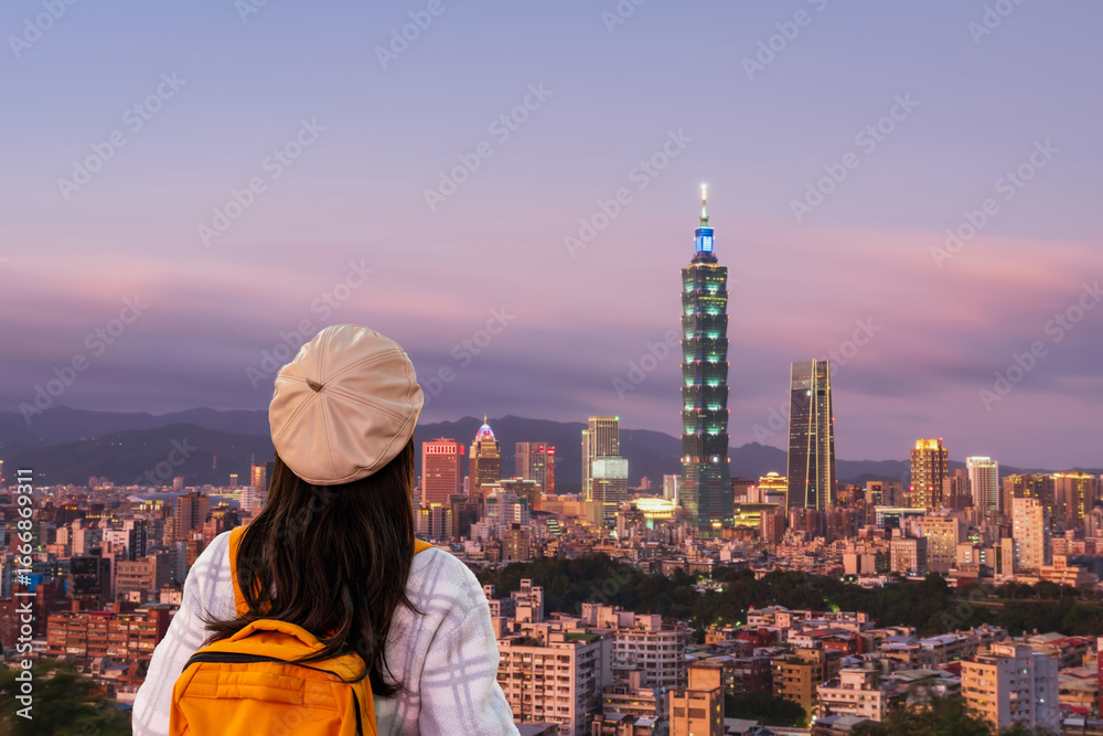 Obraz premium Young female tourist enjoying panoramic view of Taipei city skyline at sunset, travel concept