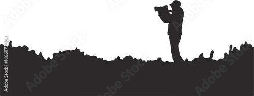 Silhouette of a person filming with a video camera in a landscape