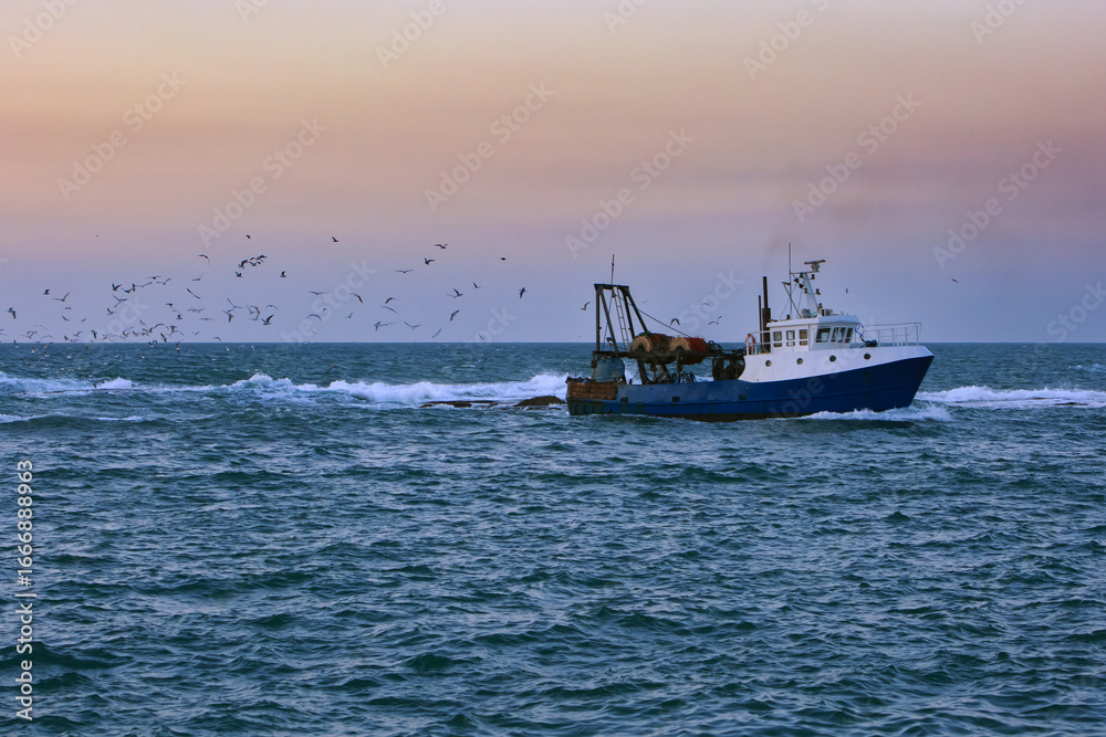 Naklejka premium Fishing boat at sunset off the coast of Jaffa, Israel