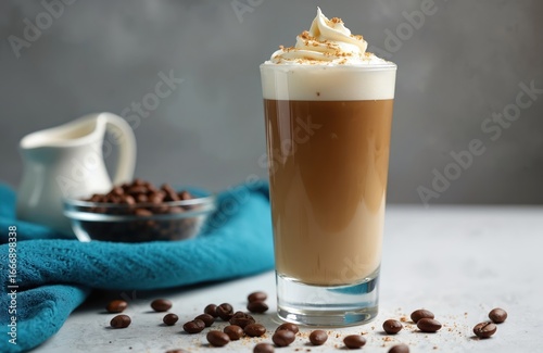 Dalgona coffee in glass cup popular Korean beverage. Frothy whipped coffee topping sits on chilled milk, creating delightful contrast. Coffee beans, creamer pitcher suggest fresh ingredients for