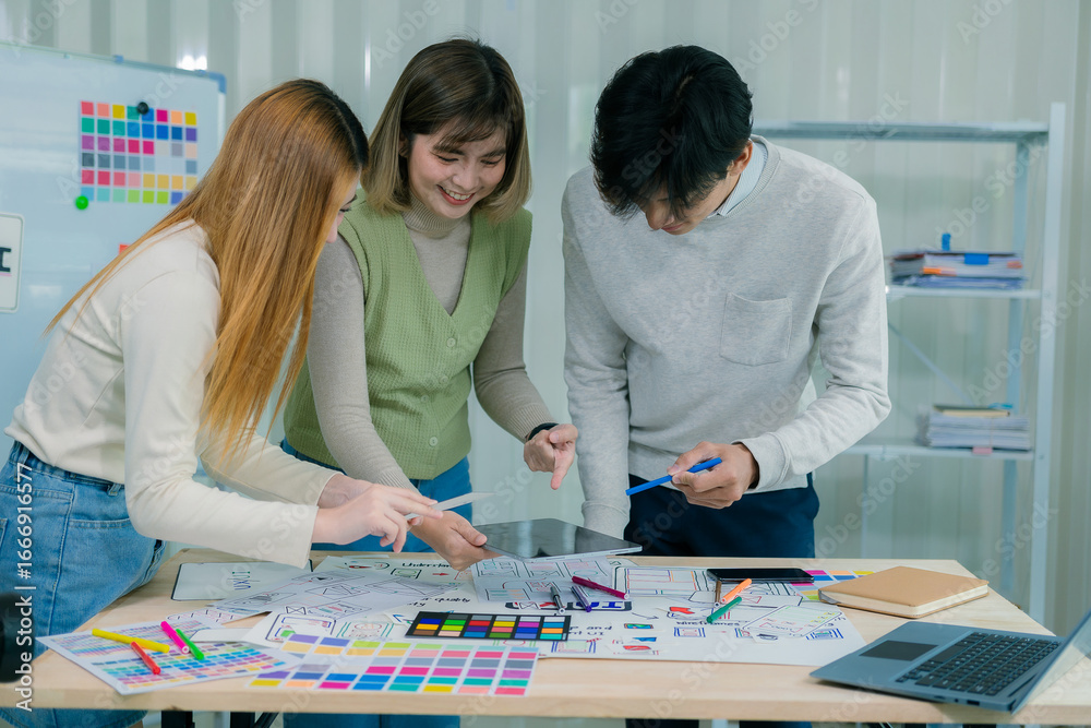Fototapeta premium A team of developers collaborates to plan UXUI designs, working on wireframes for website and mobile application prototypes, surrounded by user flow sketches and design tools.