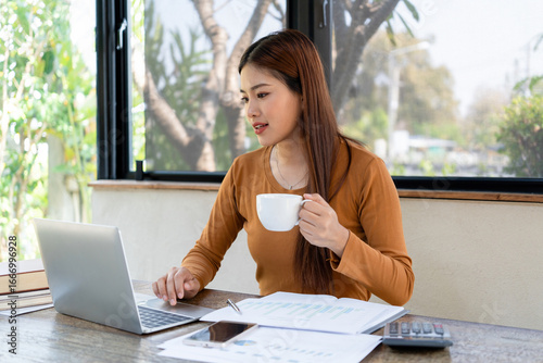 Businesswoman working while enjoying coffee.