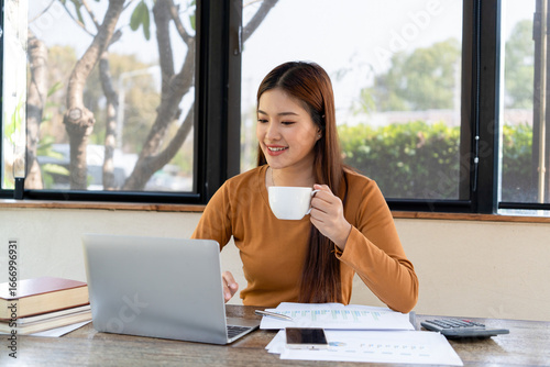 Businesswoman working while enjoying coffee.