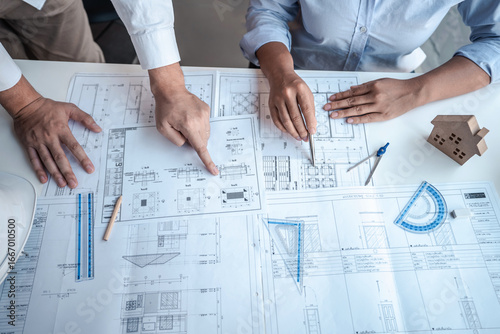 Architects or engineering team consulting and analyzing working on objects tools and construction drawings inspection planning new architectural project on blueprint and model house in modern office