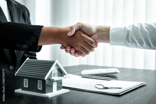 Estate agent and client are shaking hands after good deal home loan after discussing and signing contract to rent a house with approved insurance form