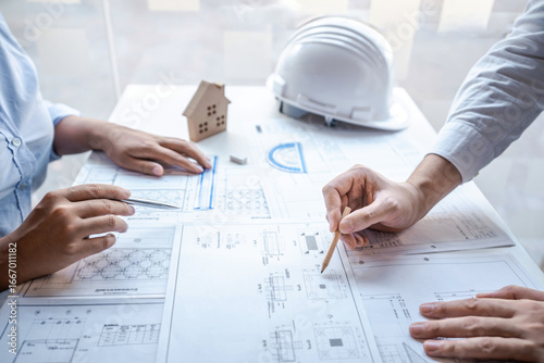 Architects or engineering team consulting and analyzing working on objects tools and construction drawings inspection planning new architectural project on blueprint and model house in modern office