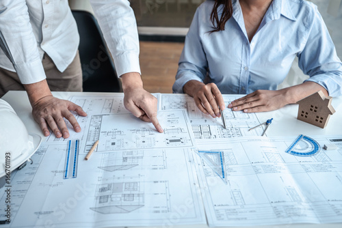 Team of architects or engineering consulting and analyzing working on objects tools and construction drawings inspection, discussing planning new architectural project on blueprint and model house