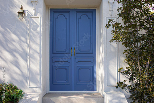 A classic blue door contrasting against a white wall.