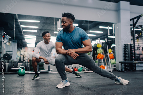 Принти на полотні Two male athletes stretching legs in modern gym
