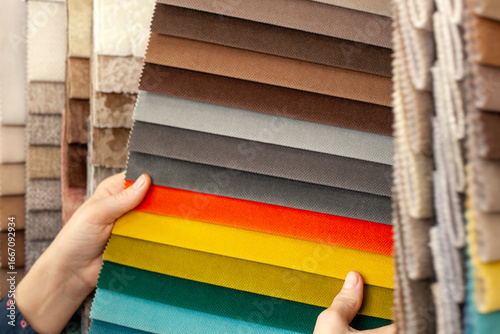 Samples of multicolored fabrics. A woman chooses a fabric for a sofa. Catalog of textiles for the manufacture of upholstered furniture. Color selection. textile industry.