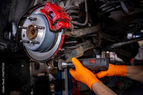 Auto Worker Cleaning Rust from Wheel Mount in Service