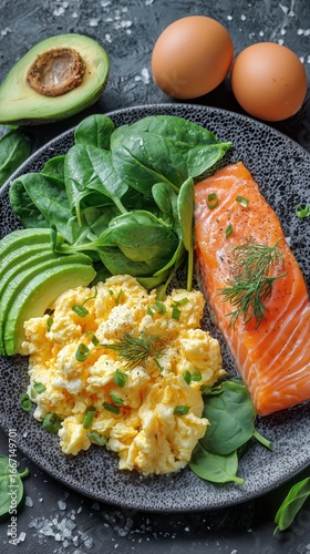 Breakfast Plate With Scrambled Eggs, Salmon, Spinach, and Avocado on Dark Tex...