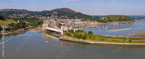 Vászonkép Aerial view of Conwy Castle, railway line, and road bridge crossing the estuary with the town and mountains in the background on a sunny summer day