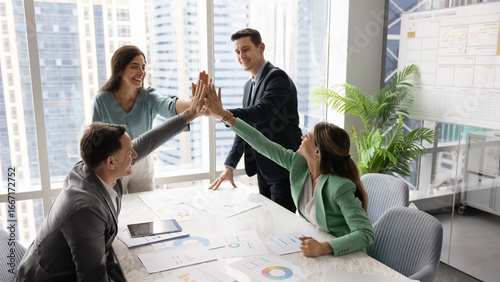Foto Diverse team of business professionals celebrate success with high-five gesture