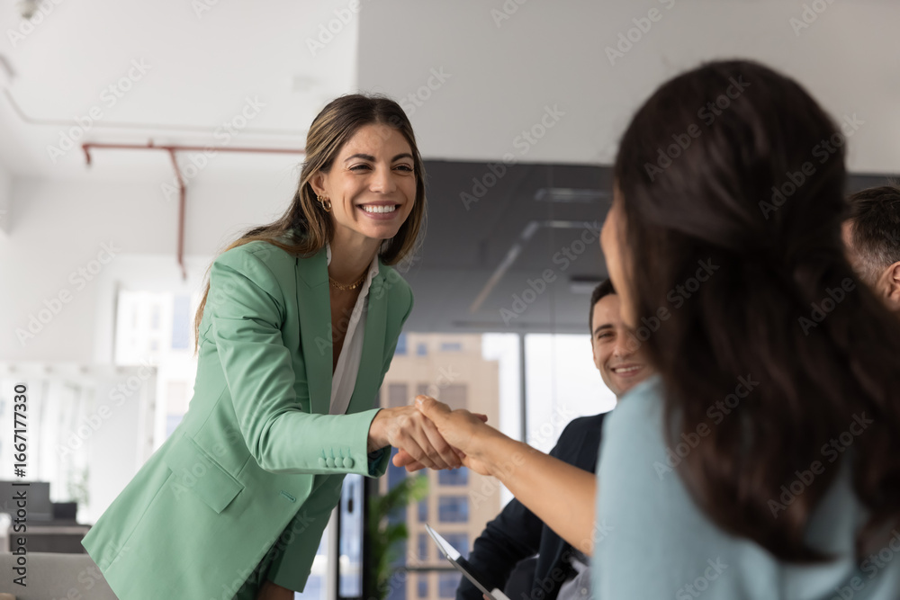 Obraz premium Happy businesswoman greeting colleague, finalize business meeting or briefing event in contemporary office. Business etiquette, gesture of making deal, start partnership and thanking for collaboration