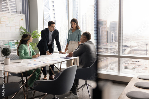 Tableau sur toile Group of four professionals engaged in srategic business planning meeting in high-rise office with panoramic city view