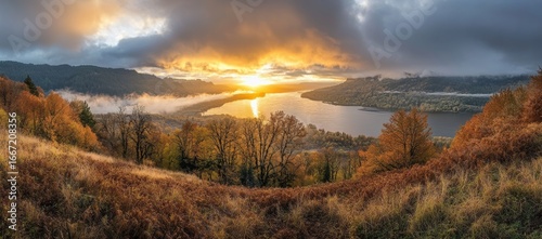 The vista house at Crown Point offers a stunning view of the Columbia River Gorge, surrounded by trees ablaze with autumn colors, shrouded in fog, in Oregon
