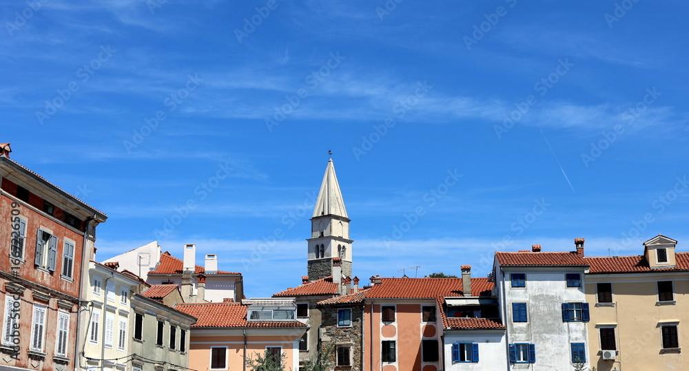 Naklejka premium Kirchturm von Izola hinter bunten Hausfaasden