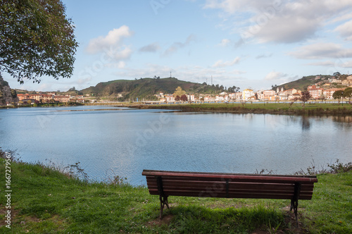 Banco vacío frente a un estuario con población en el horizonte