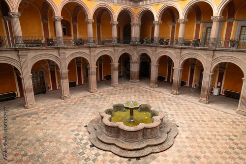 Elevated view of courtyard with central fountain, arched galleries and patterned tile floor in former monastery in Queretaro, Mexico