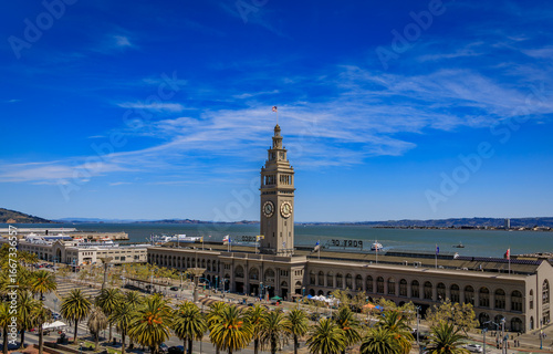Aerial view of the historic Ferry Building with the iconic clock tower and palm trees on the San Francisco waterfront in San Francisco, United States