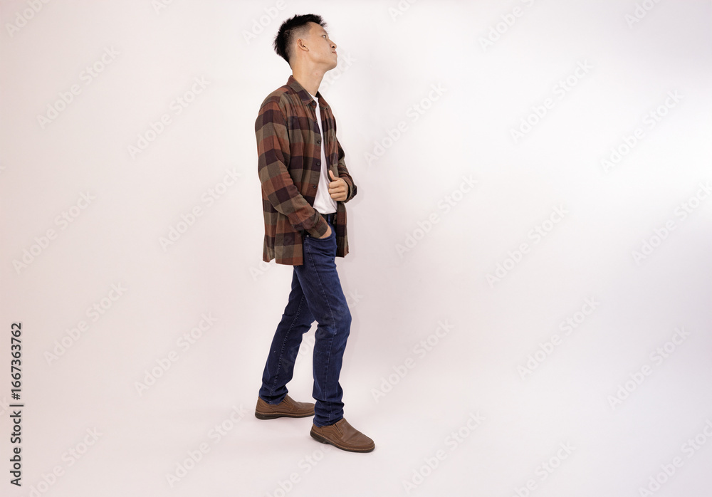 Fototapeta premium a casual young man in a plaid shirt and jeans facing away