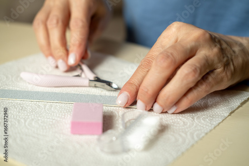 Nail care at home, close-up manicure. Using cuticle nippers, a nail file, a sanding pad, a brush and an orange stick.