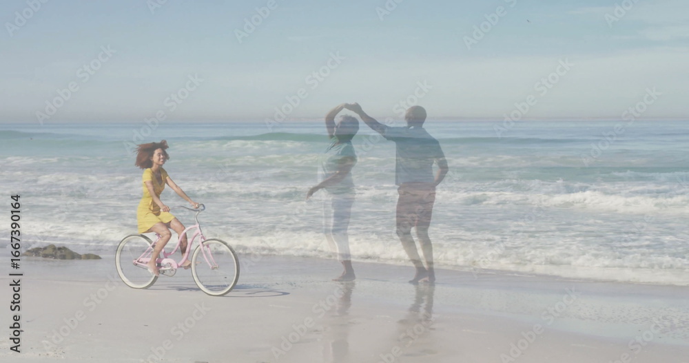 Fototapeta premium Cycling woman in yellow sundress pedaling pink bicycle at surf beach, with dancing couple reflected
