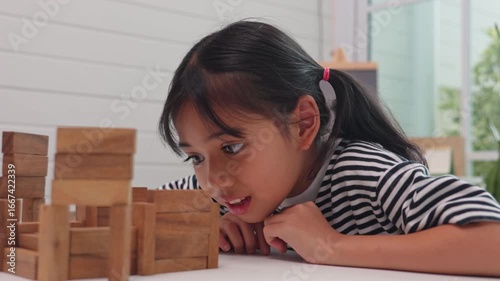 Focused girl playing and learning with wooden blocks