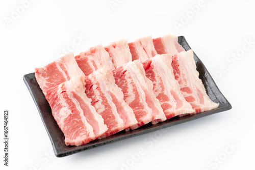 白背景にお皿に載せた焼き肉用の牛カルビ肉（牛バラ肉）