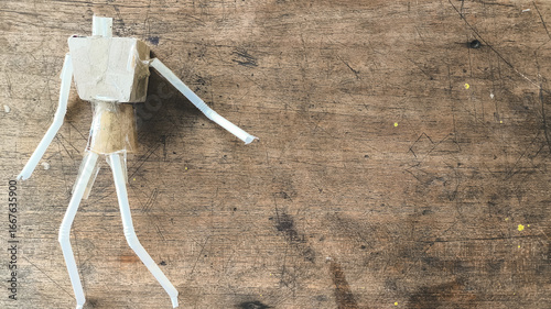 Cuadro en lienzo Recycled figure made from white plastic straws and cardboard laying on rough wooden background, showing DIY creativity and sustainability concept, ideal for eco art and craft theme content