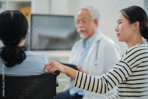 Fotografie Asian daughter accompanies senior mother for medical consultation with doctor using digital health technology