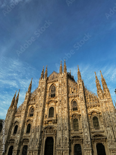 Canvastavla Dramatic low-angle view of the Milan Cathedral (Duomo di Milano) facade against a vibrant blue sky with wispy clouds