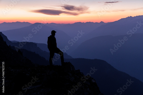 Hiker standing on summit, looking at sunset, success.