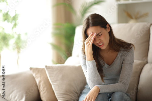 Woman suffering head ache being alone at home