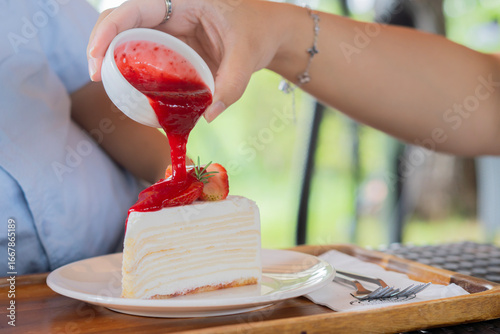 Papier peint Cropped hand pouring strawberry jam syrup on crape cake in plate