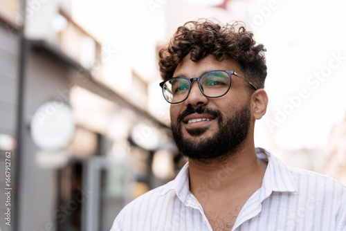 Obraz na plátně Young Indian Man Smiling and Wearing Glasses in Urban Setting