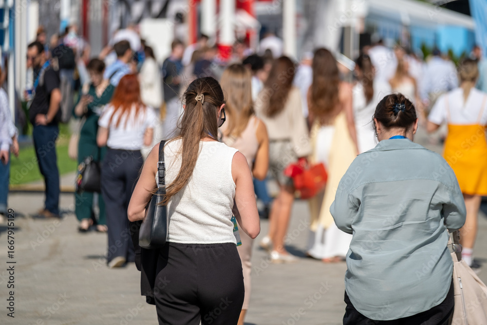 Fototapeta premium Scene depicting a crowd attending an outdoor event venue on a warm day, showing lively activity.