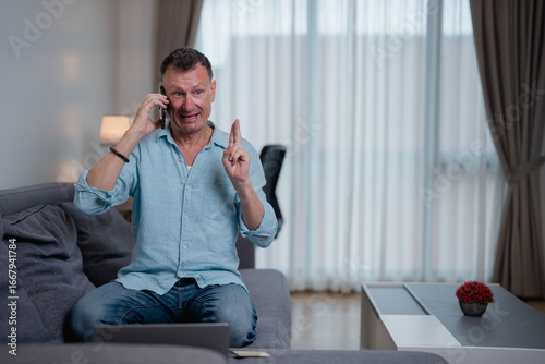 Slika na platnu Businessman working from home, sitting on the sofa with a laptop, engaged in an