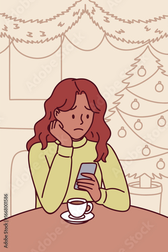 Dark-skinned girl sits alone with hot drink in festive decorated room on Christmas evening feeling sad and emotionally distant