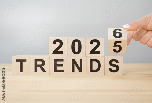 Foto Hand flipping wooden block to change year from 2025 to 2026 over TRENDS word for