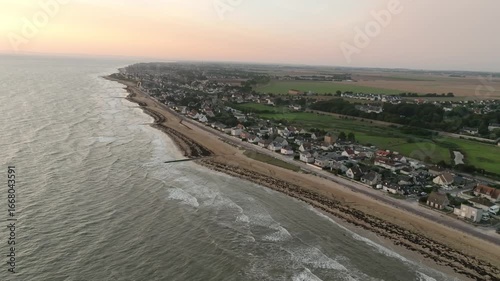 Wallpaper Mural Aerial view of the coastline where the grey ocean meets the sandy beach and the town, all under a light pink sky, Bernières-sur-Mer, Normandy, France. Torontodigital.ca