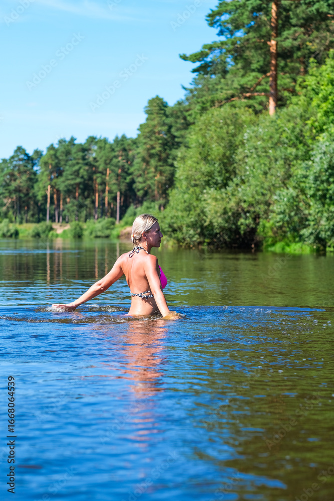 Fototapeta premium Moscow, Russia, 08.08.24. A woman in a pink bikini is in the water