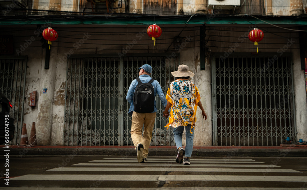 Obraz premium Happy senior couple walking on a city street, holding hands and sightseeing together,