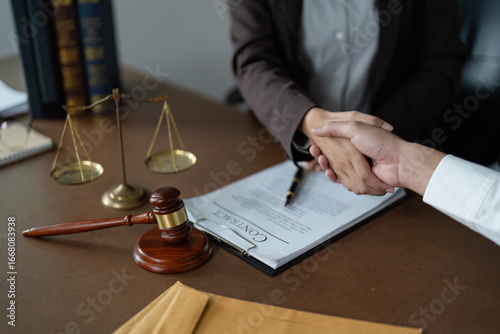 Legal Agreement. Lawyer and client shaking hands over contract on desk.