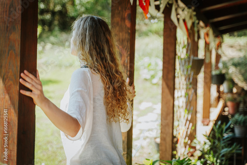 Tableau sur toile Young beautiful blonde woman with long curly hair standing on the terrace of a c