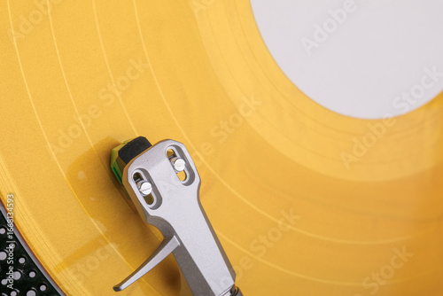 Wall Mural Macro photo of bright yellow vinyl record spinning on turntable with silver tonearm and green stylus, showcasing grooves and texture