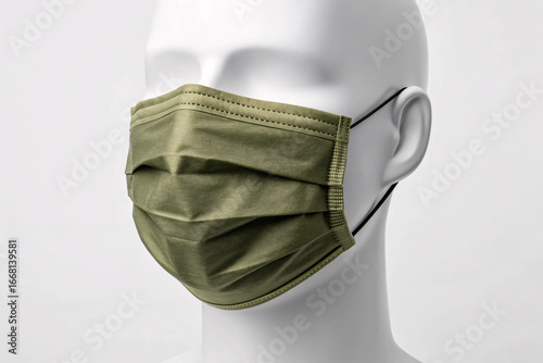 Olive green pleated face mask on white mannequin head, surgical mask with ear loops, side profile view