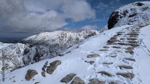 Stone steps covered in snow winding up mountain slope with rocky peaks in Tatra Mountains, Poland.